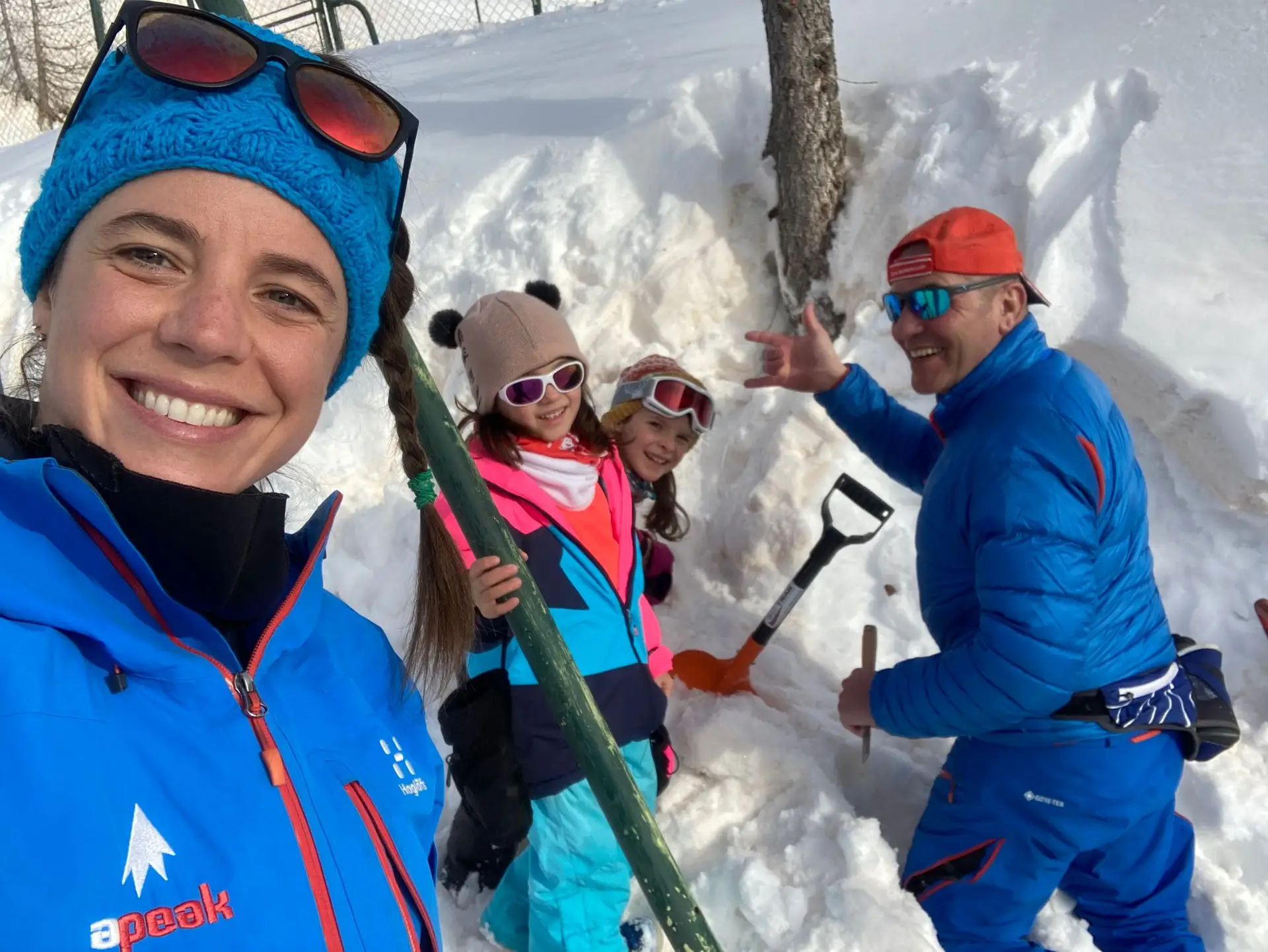 Enfants et parents construisant un mini-igloo et faisant griller des chamallows autour d’un feu de camp dans la neige.