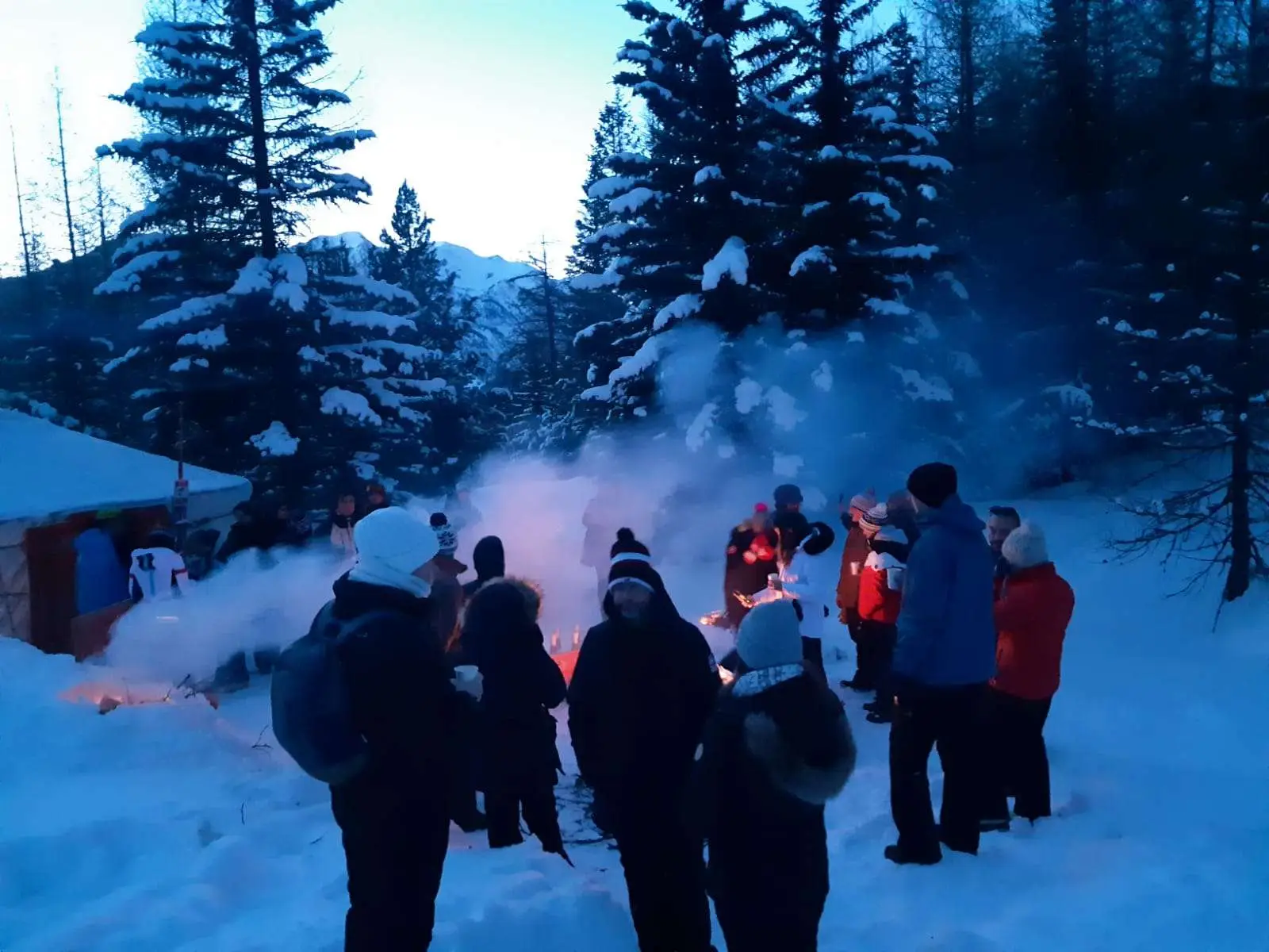 Gruppo sorridente con lampade frontali e racchette da neve ai piedi.